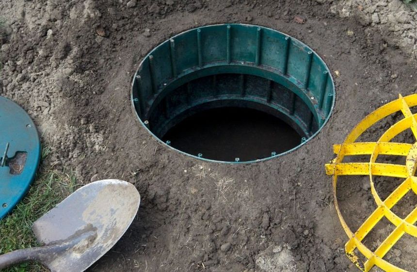 Arqueta de registro abierta junto a una vivienda, posible origen de malos olores